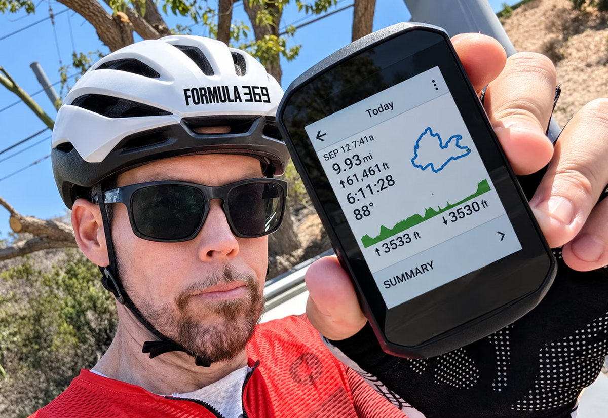Cyclist holding a bike computer after a ride